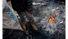Chlapec se ohřívá u ohniště na skládce v Albánii