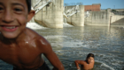 Romské děti si hrají v řece u splavu